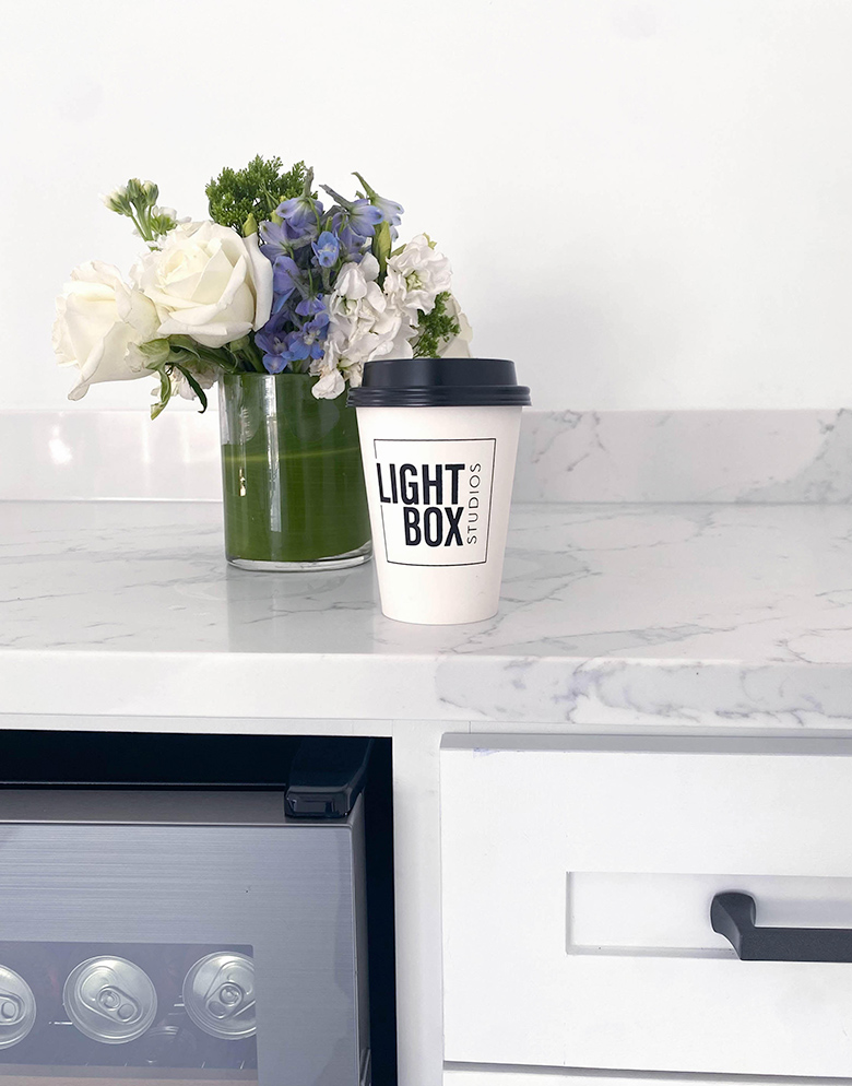 light box studios coffee cup on break room countertop in lounge area next to a green vase full of flowers reserve or book a photography studio in dallas texas
